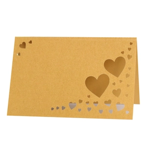 Golden laser-cut heart seat cards for weddings featuring a pearlized shimmer finish