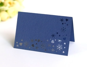 Detail of dark blue laser-cut place card with snowflake and heart cutout patterns