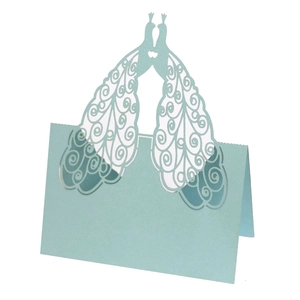 Detail of light blue laser-cut peacock place card with intricate hollow wedding patterns