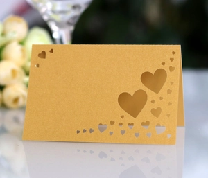 Macro shot of laser-cut heart pattern on pearlescent golden wedding table seating card