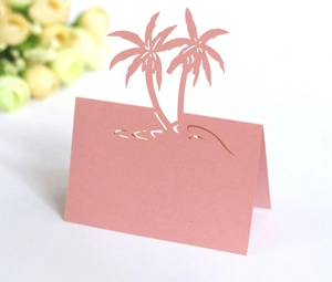 Macro view of pink laser-cut place cards with tropical coconut palm tree design