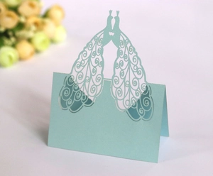Detail of laser-cut blue peacock table card with intricate hollow wedding design