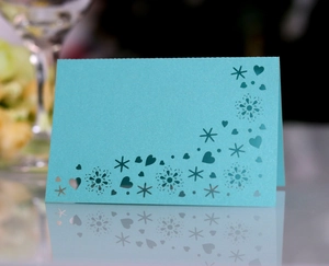 Macro shot of laser-cut tiffany blue table card with delicate snowflake and heart patterns