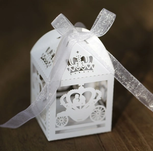 Macro view of white laser-cut wedding candy box with crown and carriage hollow patterns