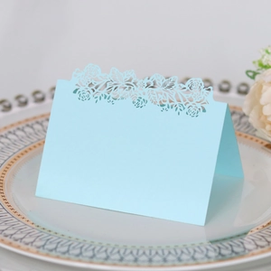 Detail of light blue laser-cut place card with floral patterns on a ceramic plate