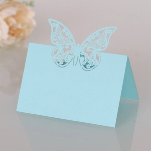 Macro detail of laser-cut light blue butterfly place card with intricate patterns