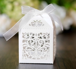 Detail of laser-cut hollow floral pattern on white gift box with silver silk ribbon bow