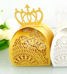 Detail of laser-cut crown candy boxes in gold and white with intricate lace hollow patterns