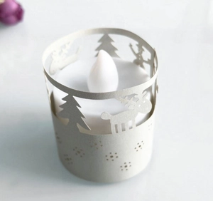 Detail einer weißen LED-Kerze mit lasergeschnittener Weihnachtshülle und Rentier-Motiv