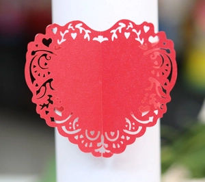 Close-up of laser-cut red paper napkin ring with intricate heart hollow design