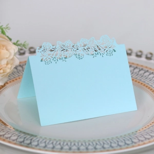 Detail of light blue laser cut place card with elegant floral pattern on table