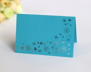 Detail of laser-cut heart and floral patterns on bright blue folded wedding place cards