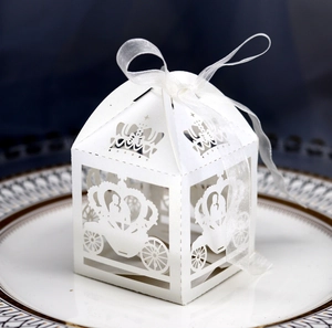 Macro shot of laser-cut white wedding favor box with carriage crown and ribbon bow