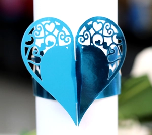 Detailed close-up of a blue heart-shaped napkin ring with elegant hollow laser-cut patterns