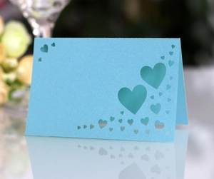 Macro detail of laser-cut heart hollow design on light blue pearlescent table card