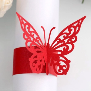 Red laser-cut butterfly napkin ring with intricate vine patterns on white background
