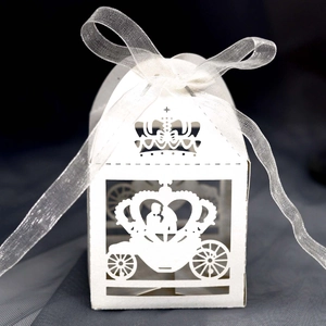 Close-up of laser-cut crown and carriage design on white wedding favor box with ribbon