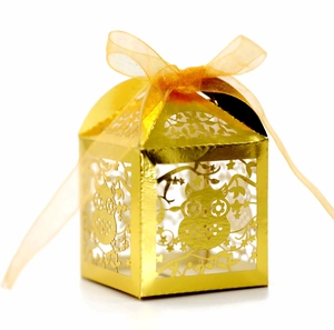 Detail of gold laser-cut owl favor box with intricate hollow design and sheer ribbon bow