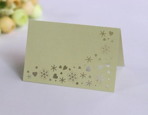 Detail of laser-cut snowflake and heart patterns on olive green foldable place card