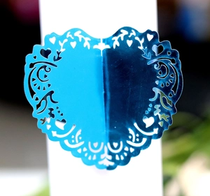 Detail of laser-cut heart napkin ring in bright blue with intricate vine patterns