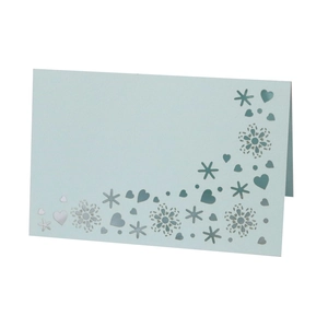 Macro detail of laser-cut snowflake and heart patterns on light blue paper place card
