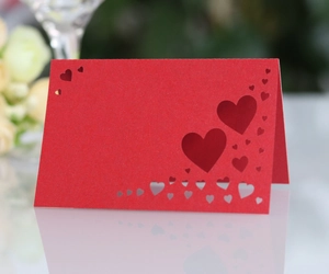 Close-up of red laser-cut place card with hollow heart pattern for wedding tables