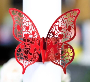 Detail of red laser-cut butterfly napkin ring with hollow heart and floral patterns