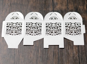 Flat lay of laser-cut wedding favor box with ornate European floral patterns on white paper
