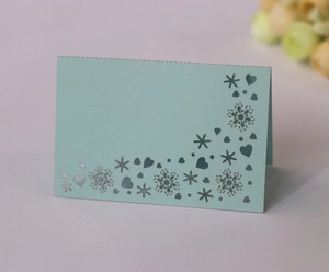 Detailed laser-cut mint blue place card with snowflake and heart patterns for wedding decor