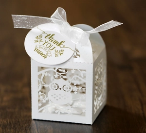 Close-up of hollow owl design on white gift box with silk ribbon and thank you tag