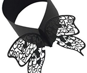Detail of laser-cut black paper butterfly napkin rings featuring intricate heart patterns