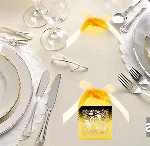 Detail of laser-cut gold gift boxes with rose patterns and yellow ribbon on a table