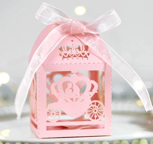 Pink laser-cut wedding favor box with pumpkin carriage design and white ribbon bow