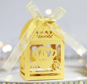Close-up of yellow laser-cut carriage wedding favor box with an elegant ribbon bow