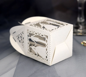 Detail of laser-cut white wedding favor box featuring bride and groom silhouette design