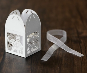 Detailed laser-cut elephant pattern on a white cardstock wedding favor box with a silk ribbon