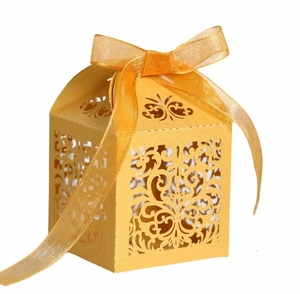 Close-up of laser-cut European vine pattern on yellow wedding candy gift box with ribbon