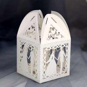 Macro view of white pearlescent paper wedding favor box with laser-cut silhouettes