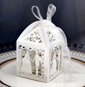 Detail of laser-cut wedding favor box with bride and groom silhouette and ribbon