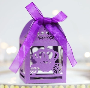 Detail of purple laser-cut pumpkin carriage wedding favors box with a satin ribbon bow