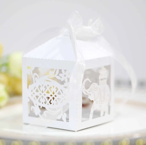 Detail of white laser-cut wedding candy box with elephant pattern and sheer ribbon