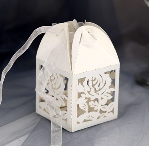 Close-up of laser-cut white rose floral pattern on a wedding candy gift box with ribbon