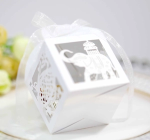 Detailed laser-cut white favor box with elephant pattern and white organza ribbon