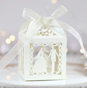 Close-up of laser-cut wedding favor box with bride and groom silhouette and white ribbon