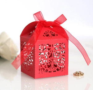 Close-up of red laser-cut wedding favor box with pearl paper texture and silk ribbon bow