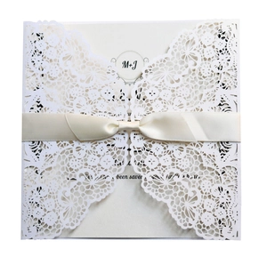Elegant cream laser cut wedding invitation set with intricate lace detail and satin ribbon