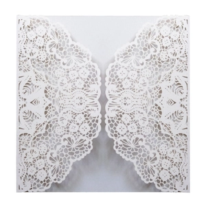 Detail of white laser-cut wedding invitation with intricate lace flower pattern