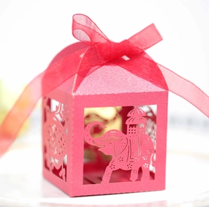Detail of pink laser-cut wedding favor box with elephant pattern and satin ribbon