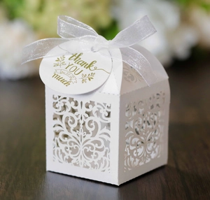Detail of white laser-cut wedding favor box with silver ribbon and Thank You tag