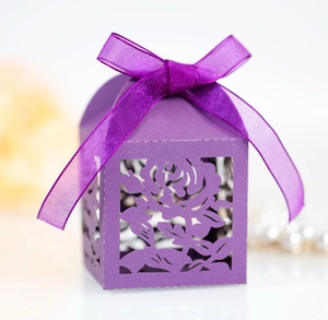 Detail of laser-cut rose patterns on a purple cardstock wedding favor gift box with ribbon